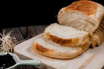 Close up fresh homemade loafs bread and sliced bread on cutting board with jam strawberry on wooden background.Healthy Diet.Prepared from a dough of flour and water, usually by baking.