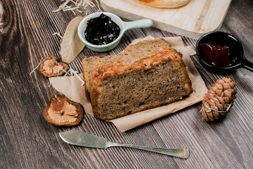 Close up Homemade delicious freshly baked classic sweet banana bread sliced with blueberry/strawberry jam and butter knife on a wooden kitchen Table in rustic style.Ideas recipe healthy diet breakfast