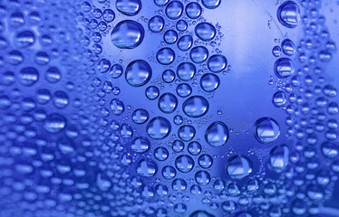 Close up water drops on purple tone background. Abstract purple tone wet texture with drops on glass surface. 