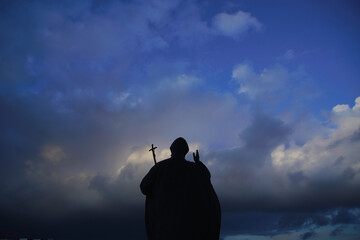 Great big Christian holy statue monument and shrine of Pope John Paul II from Catholic Church Vatican City State against background of cloudy evening spring winter sky in blue, purple tones