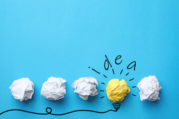 Idea concept. Crumpled paper balls, drawing of lamp bulb and space for text on blue background,...