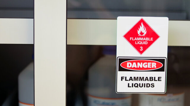 Chemical hazard sign pictogram, Globally Harmonized System of Classification and Labelling of Chemicals (GHS). Flammable liquid danger warning caution sticker with container bottle in storage cabinet.