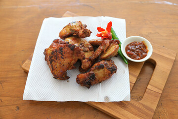 Photo of fried chicken food served with hot chili sauce and decorated with tomatoes and green chili