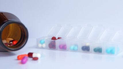 Close up brown drug bottle with colorful capsules of antibiotic, isolated in white background with Pill box daily take a medicine, with colorful of pills, tablets, use for treatment. has a copy space.
