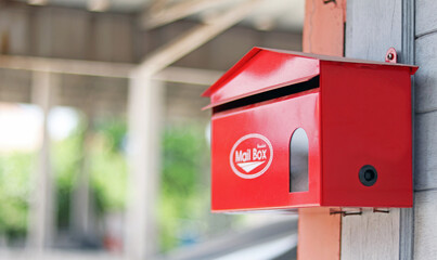 Red mail box or post box set up on the wooden wall for sending and receiving the mails and parcels. work from home and quarantine service, isolated in green bokeh blur background, has a copy space.