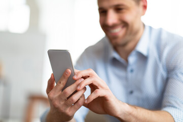 Cheerful adult man using smartphone at home