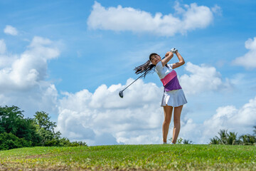 Gorgeous golfer lady hitting ball on professional golf course.