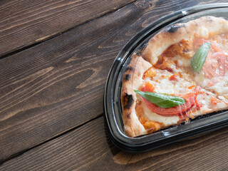 持ち帰り容器に入ったトマトとバジルのチーズピザ。