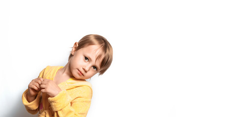 Little cute girl in a yellow bathrobe posing funny on a white background.
