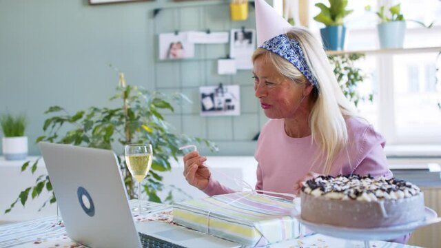 Senior woman with laptop indoors at home, celebrating distance birthday.