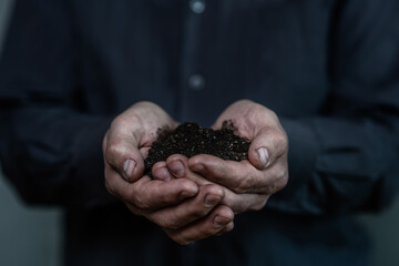 Old man's dirty hands hold earth handful. Earth day concept