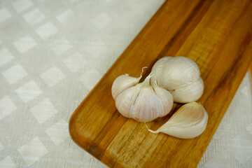 Garlic cloves on wooden board with white stuff background