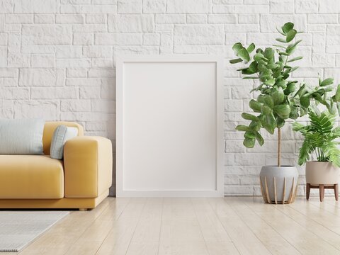 Poster mockup with vertical frame standing on floor in living room interior with yellow sofa.