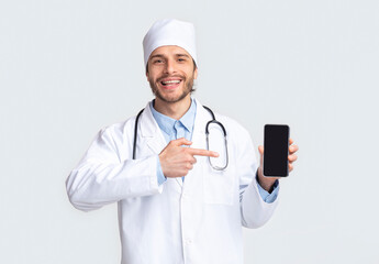 Happy doctor presenting mobile phone with blank screen