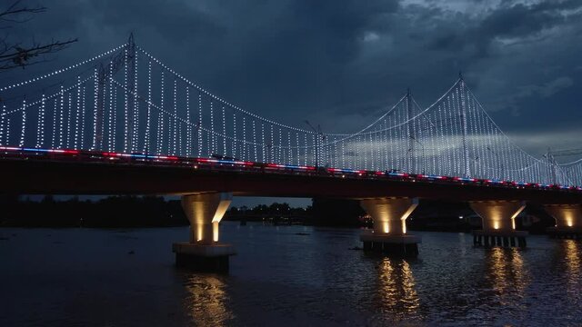 The scenery of the Tapi river bridge with the colorful light decoration at dusk in Surat Thani province, Thailand.