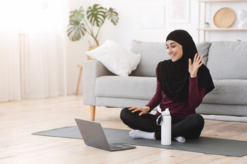 Interactive Yoga. Smiling Muslim Woman Training With Online Coach, Waving At Laptop