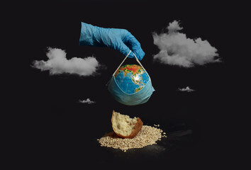 The concept of the agricultural crisis during the virus and quarantine. A gloved hand holds a medical mask, in the background lies a handful of grain and spikelets of wheat