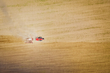 A tractor plows fields for sowing crops. View from above. Tractor in the field. Agricultural activity. Aerial view