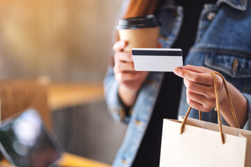 A woman holding shopping bags , credit card and coffee cup for online shopping concept - obrazy, fototapety, plakaty