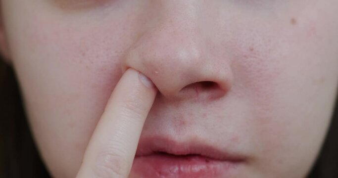 close-up of a girl's nose, finger picking her nose