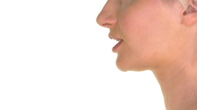 Closeup on lips of a young woman applying finger to lips - gesturing silence