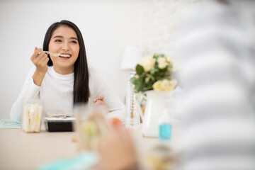 Young Asian  woman sitting separated in restaurant or home  eating food with table protect infection from coronavirus covid-19, new normal restaurant and social distancing concept.