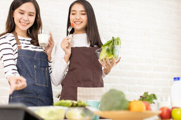 Young asian woman and happy   eating healthy salad sitting on the table with green fresh ingredients indoors.greens in bowl for breakfast or lunch. Vegan vegetarian healthy food.