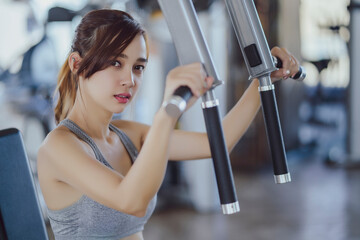 Fototapeta na wymiar fitness new normal, Woman at the gym on a sports simulator., Fit beautiful young woman exercise workout on machine in gym. Glad smiling girl is enjoy with her training process. Concept of fitness, Hea