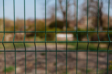Steel grill fence with blurred wire background