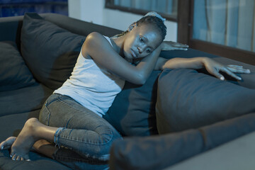 young African American woman suffering depression - sad and depressed black teenager girl in pain at home sofa couch feeling overwhelmed and emotional crying