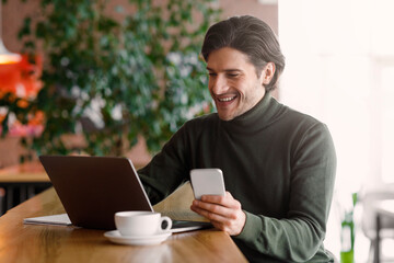 Emotional entrepreneur working online, using laptop and smartphone