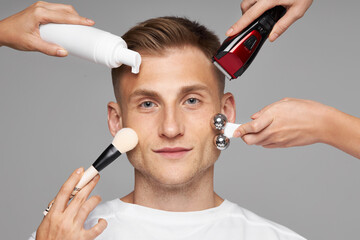 Men's cosmetology. Facial care for an African model. Jade Roller, electric razor, makeup brushes and liquid in a bottle near a person's face.