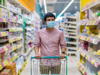 asian man with shopping cart in supermarket department store and her wearing medical mask for prevention coronavirus(covid-19) pandemic. new normal concept