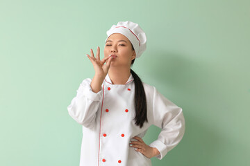 Beautiful Asian chef on color background