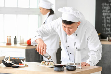 Handsome Asian chef cooking in kitchen