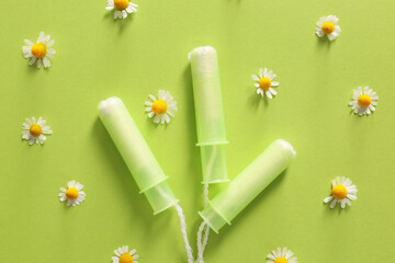 Menstrual tampons with chamomile flowers on color background - obrazy, fototapety, plakaty