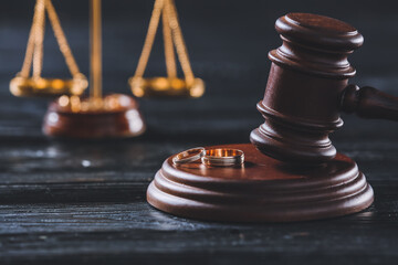 Judge gavel with wedding rings on dark wooden background