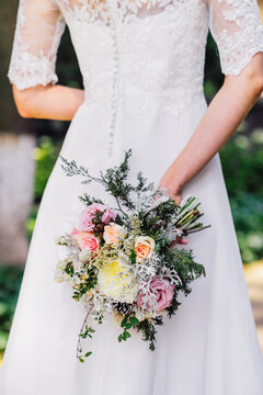 Brides back in a lace wedding dress with wedding bouquer made of pink and white roses