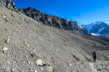 Naklejka premium A woman trekking to the top of Thorung La Pass, Annapurna Circuit Trek, Nepal. Harsh and barren landscape around. Clear and blue sky. Snow capped mountains. Early morning and cold temperature.