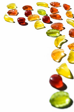 Colorful jelly beans in fruits shapes. Top view of positive and sweet composition on white background with copy space.