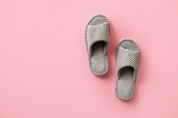 Pair of soft slippers on color background