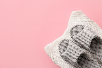 Pair of soft slippers and clothes on color background