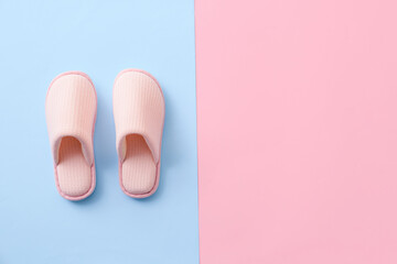 Pair of soft slippers on color background