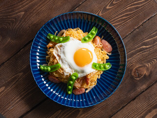ソーセージとスナップエンドウのエスニック料理ミーゴレンと、上に乗った目玉焼き。