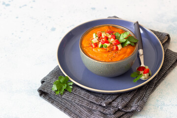 Bowl with tomato gazpacho soup garnish with cucumber and tomato. Spanish cuisine. Grey stone background.