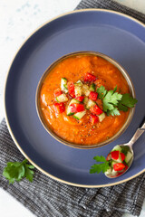 Bowl with tomato gazpacho soup garnish with cucumber and tomato. Spanish cuisine. Grey stone background. Top view.