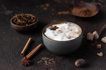 Hot chocolate or hot cocoa with anise star and cinnamon sticks over dark texture background. Selective focus.