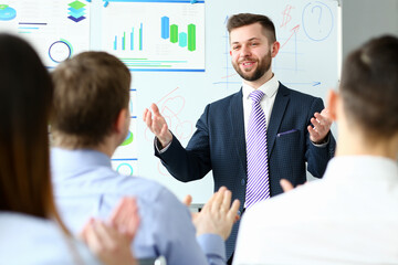 Young handsome teacher man in suit with workgroup seminar board with chart coaching background. Lecturer for applicants retraining financial statistics management enterprise etiquette corporate spirit