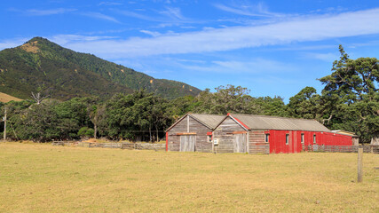 Fototapeta na wymiar Old wooden barns in mountainous rural landscape. Photographed on the Coromandel Peninsula, New Zealand