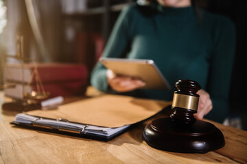 Justice and law concept. Female judge in a courtroom with the gavel working with digital tablet computer docking keyboard on wood table.